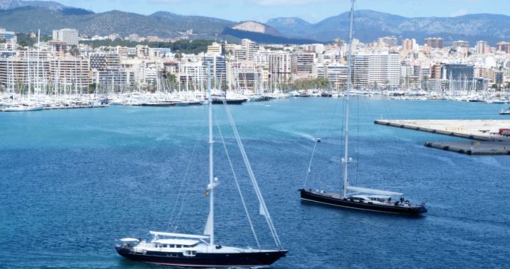 Dos grandes veleros navegan por la bahía de Palma con el puerto deportivo y la ciudad al fondo