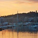 Embarcaciones amarradas en el puerto de Palma al atardecer, con el castillo de Bellver al fondo