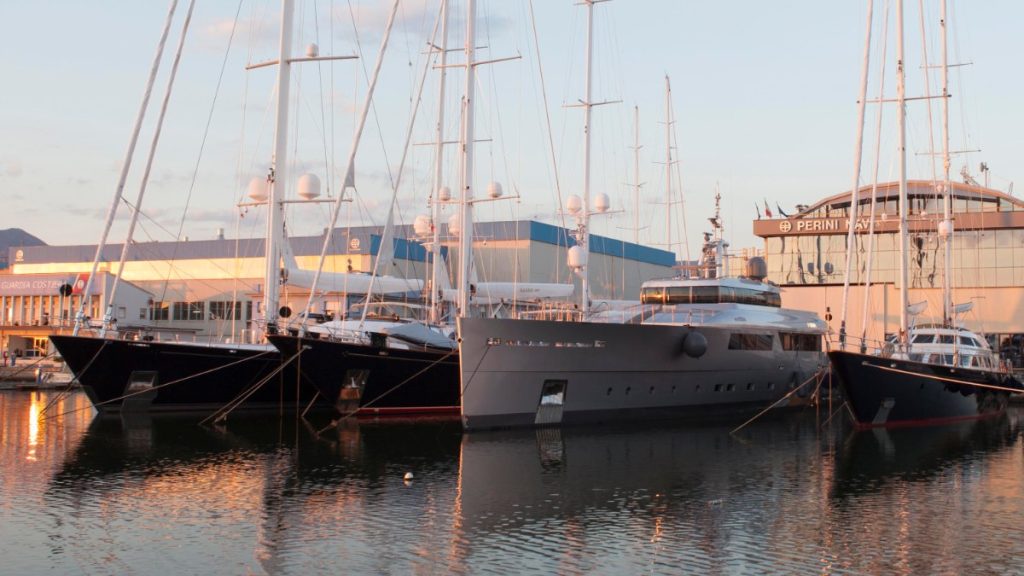 Grandes veleros y un superyate a motor amarrados frente a la sede de Perini Navi en Viareggio, al atardecer