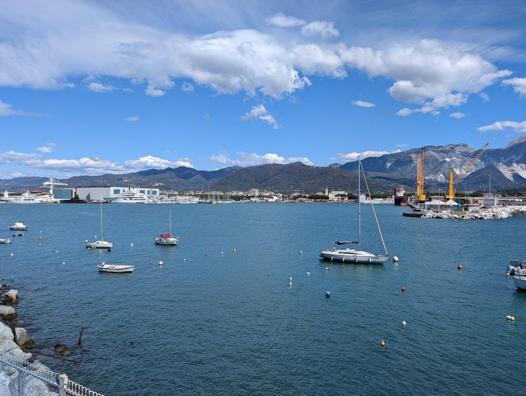 Foto de archivo del puerto de Marina di Carrara, donde tiene su sede The Italian Sea Group, con veleros fondeados y los Alpes Apuanos al fondo, vista desde el paseo Sandro Pertini en marzo de 2025