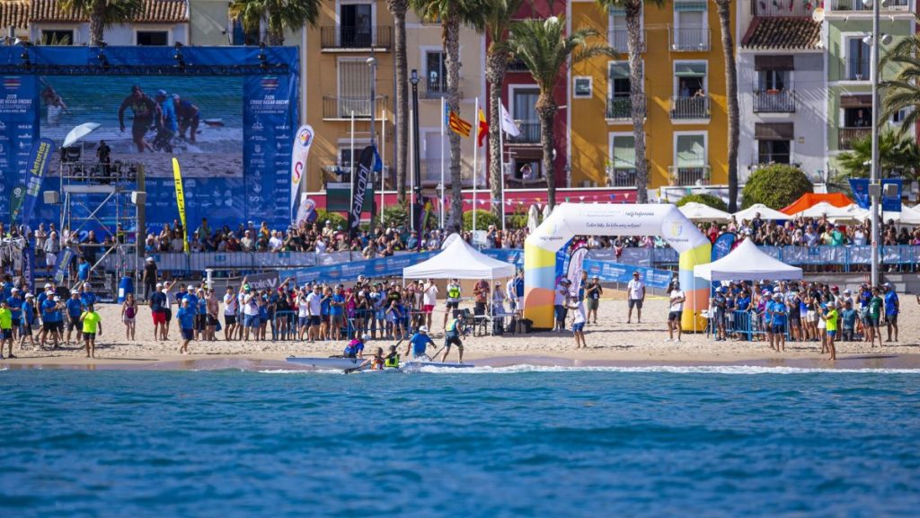 Una tripulación de surfski doble llega a la orilla de la playa Centro de Villajoyosa, junto al arco de meta y ante el público del Mundial de kayak de mar