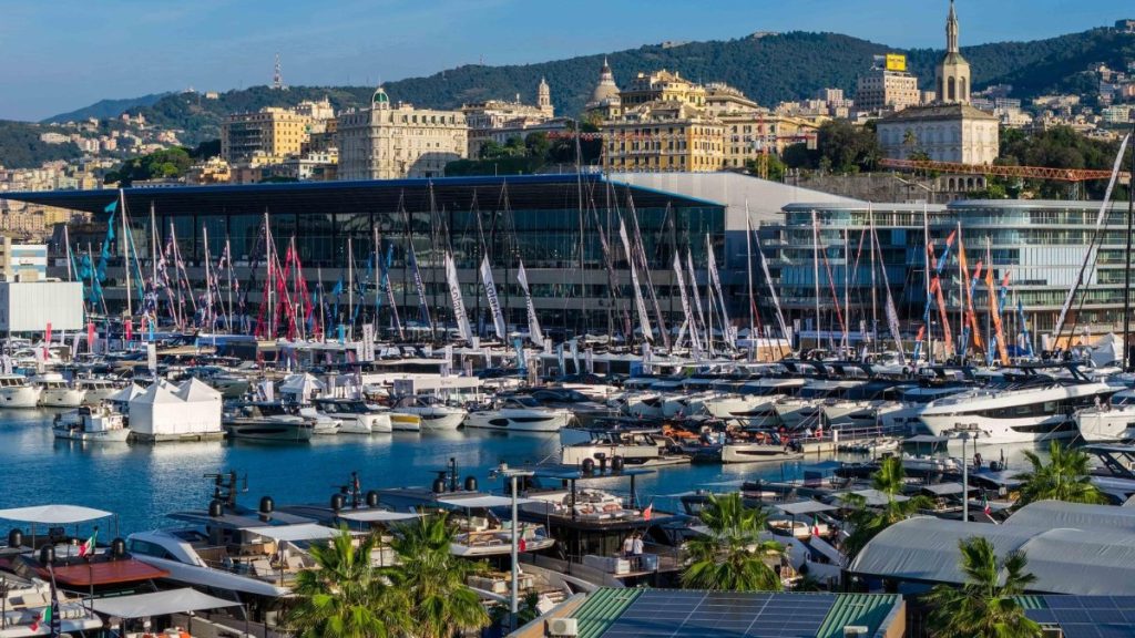 Vista elevada de los pantalanes con barcos expuestos y el pabellón del 66.º Salón Náutico de Génova en el Waterfront di Levante, con la ciudad al fondo