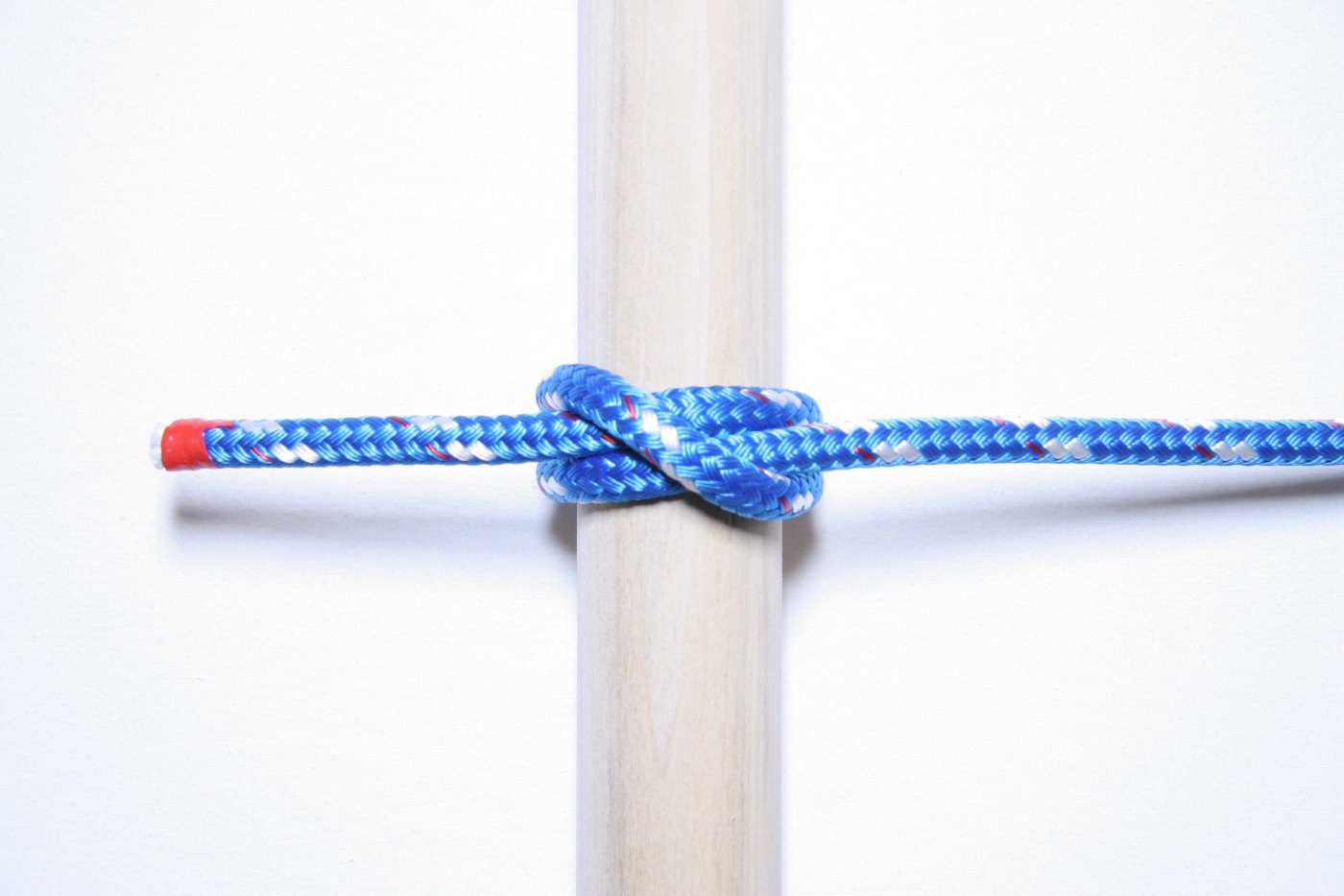 Ballestrinque hecho con un cabo azul alrededor de un palo de madera