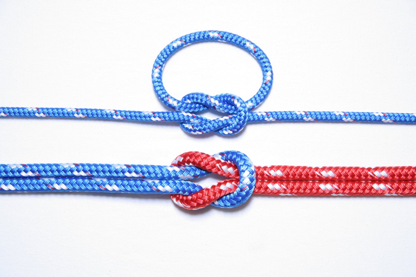 Dos nudos llanos: uno cerrando un lazo de cabo azul y otro uniendo un cabo azul y uno rojo