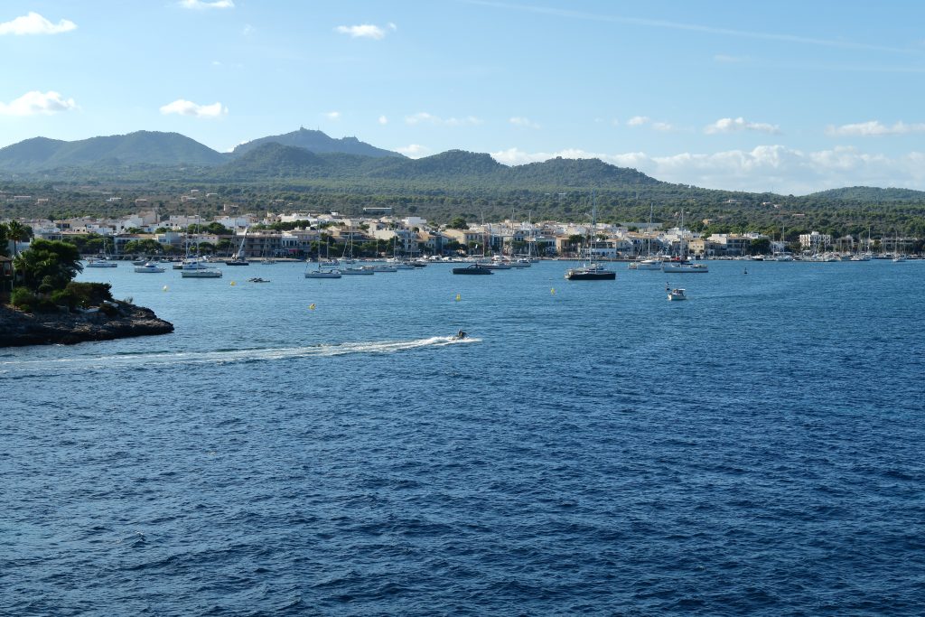 Bahía de Portocolom, en Mallorca, con veleros y lanchas fondeados frente al pueblo