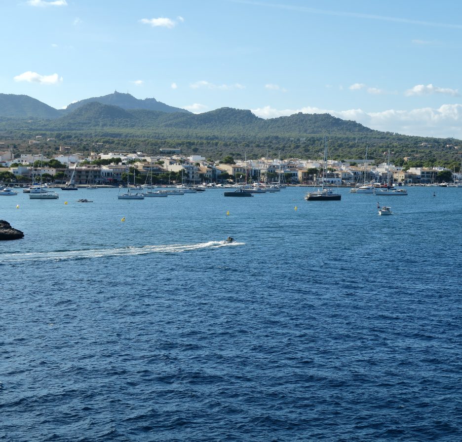 Bahía de Portocolom, en Mallorca, con veleros y lanchas fondeados frente al pueblo