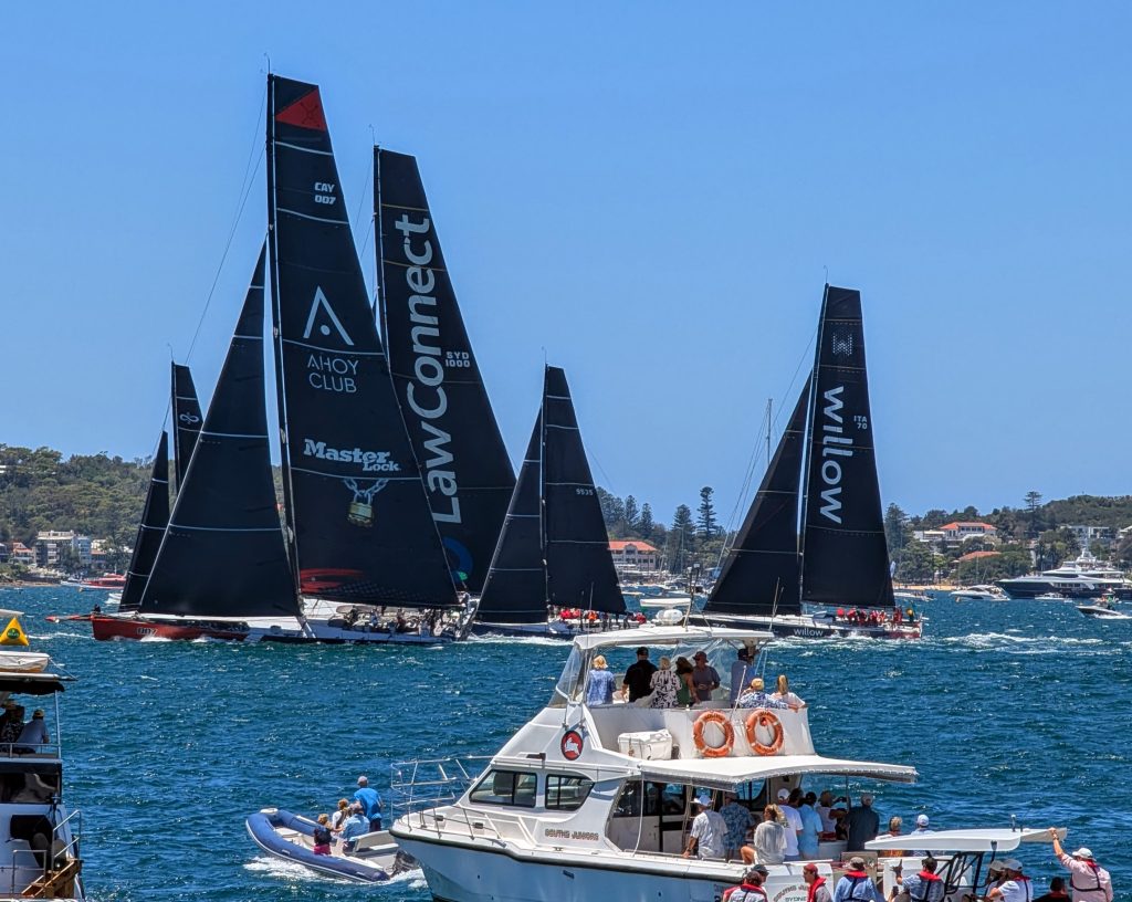 Los maxis MasterLock Comanche y LawConnect, entre otros barcos, en el disparo de salida de la Rolex Sydney Hobart de 2024 en la bahía de Sídney
