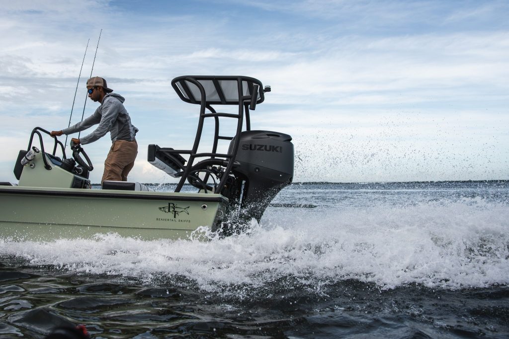 Pescador al timón de un bote de bajos impulsado por un fueraborda Suzuki negro mate navegando a velocidad